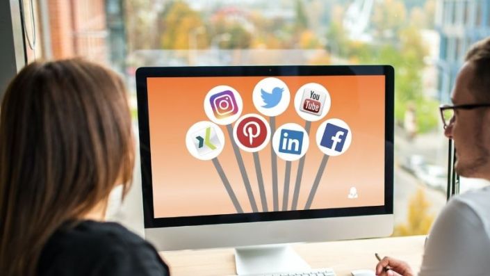 pr-doktor-titelbild Zwei Menschen schauen sich auf einem Bildschirm Social-Media-Symbole an